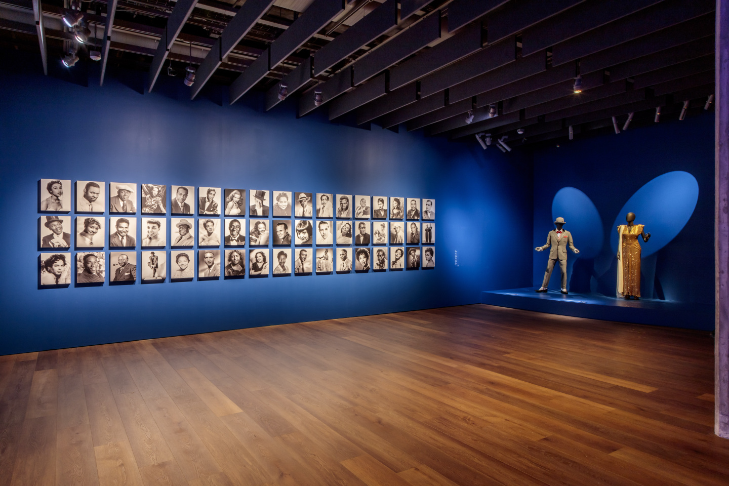 Installation view of a wall with Black actors and creatives on display.