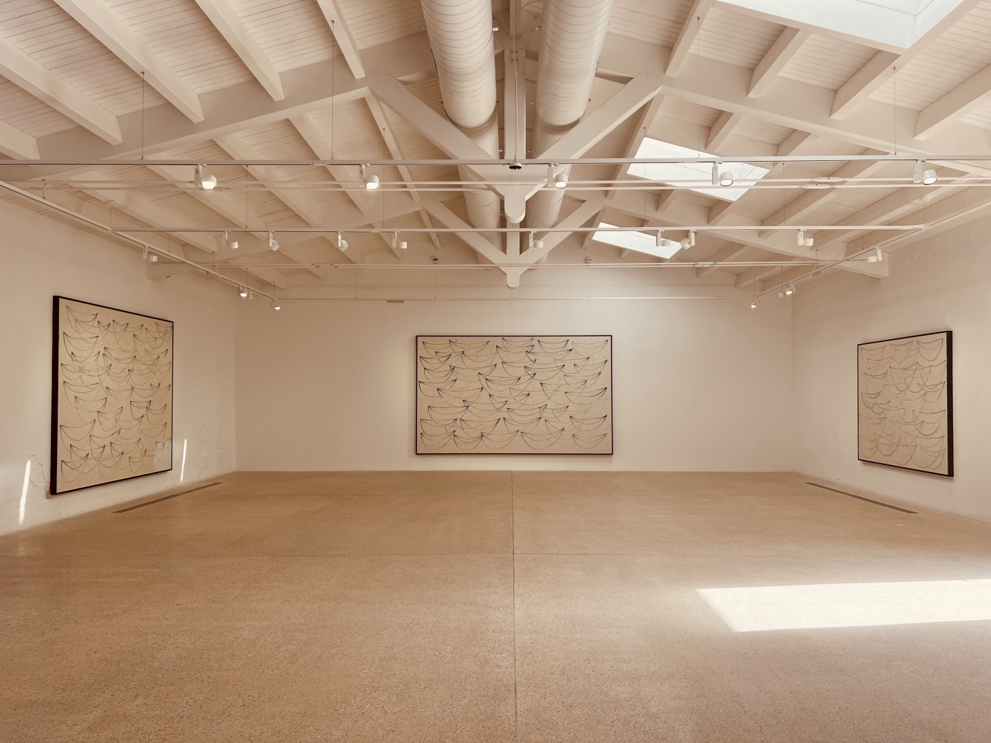 Three paintings in a gallery.