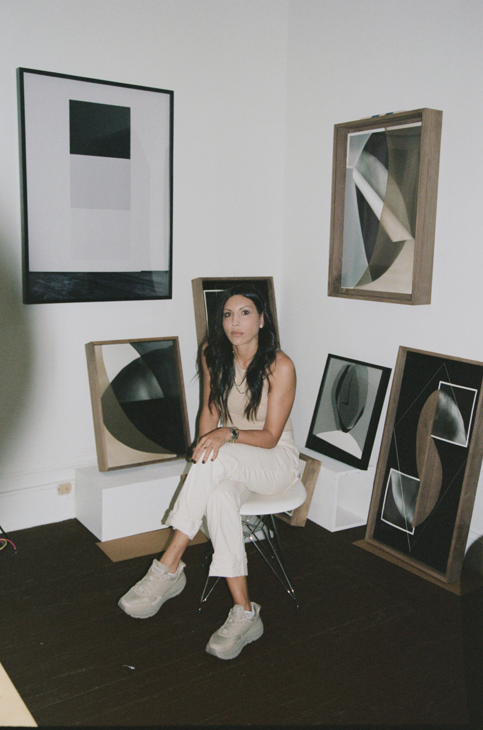 Artist sitting in front of wall with paintings hanging