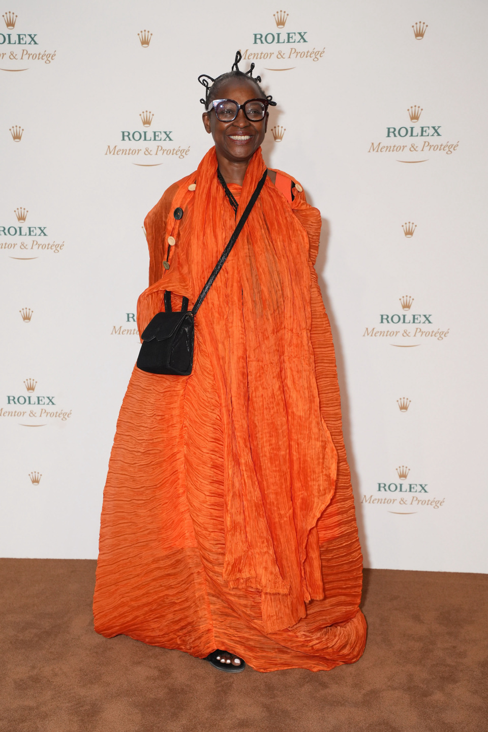 A woman in an orange dress posing for a photo.
