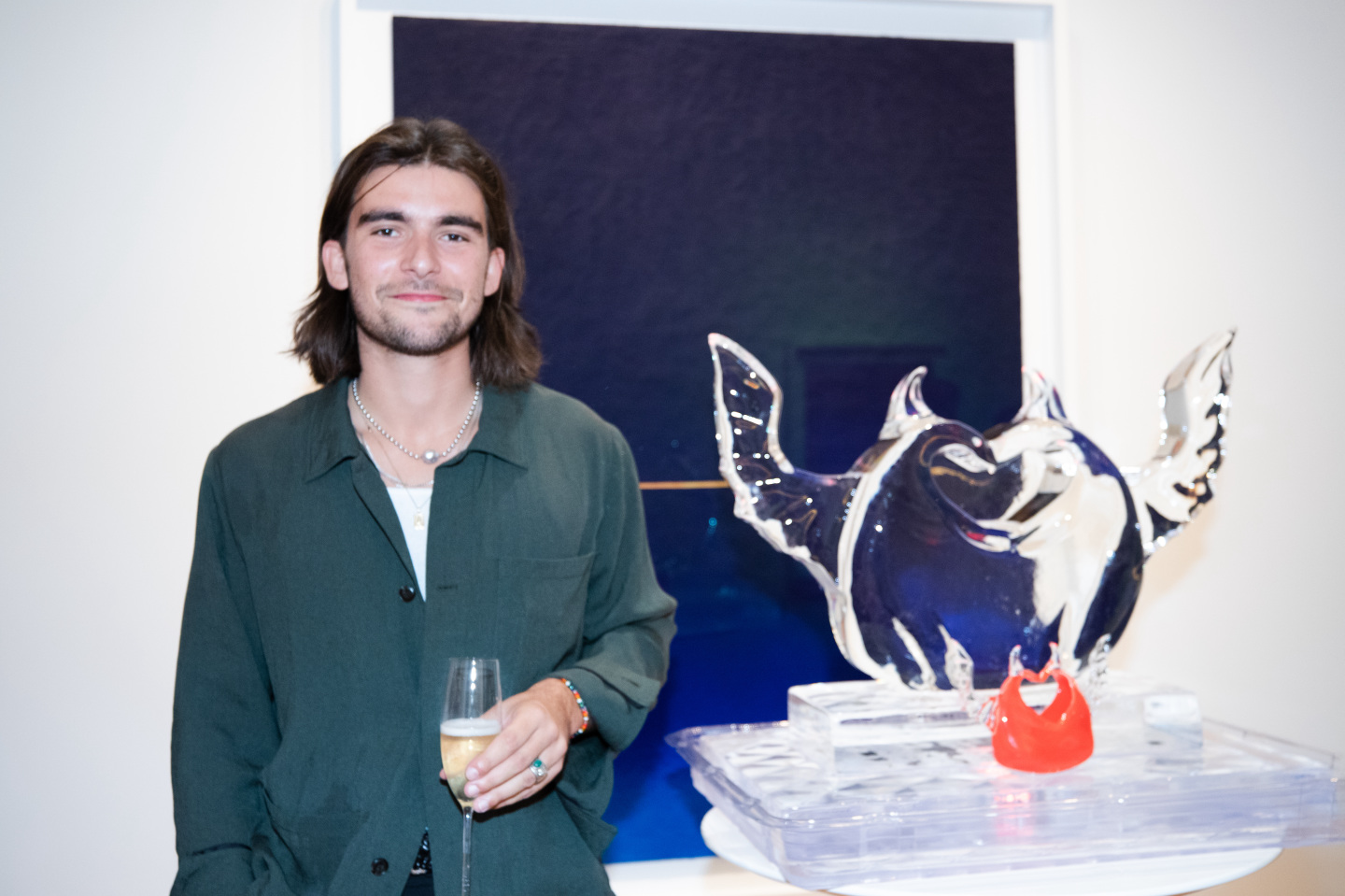 Man standing in front of a painting and ice sculpture.