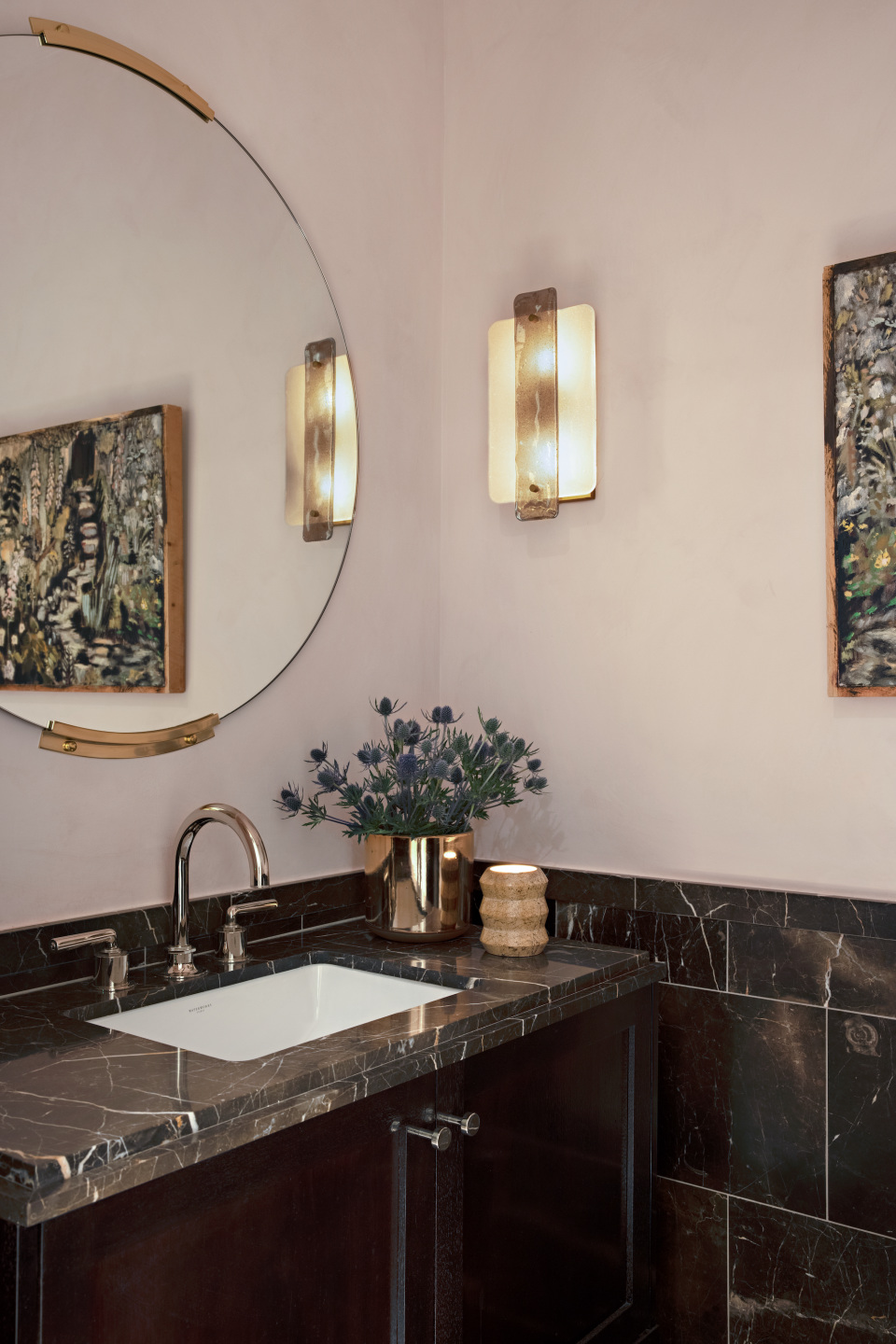 bathroom sink with round mirror with reflection of abstract painting