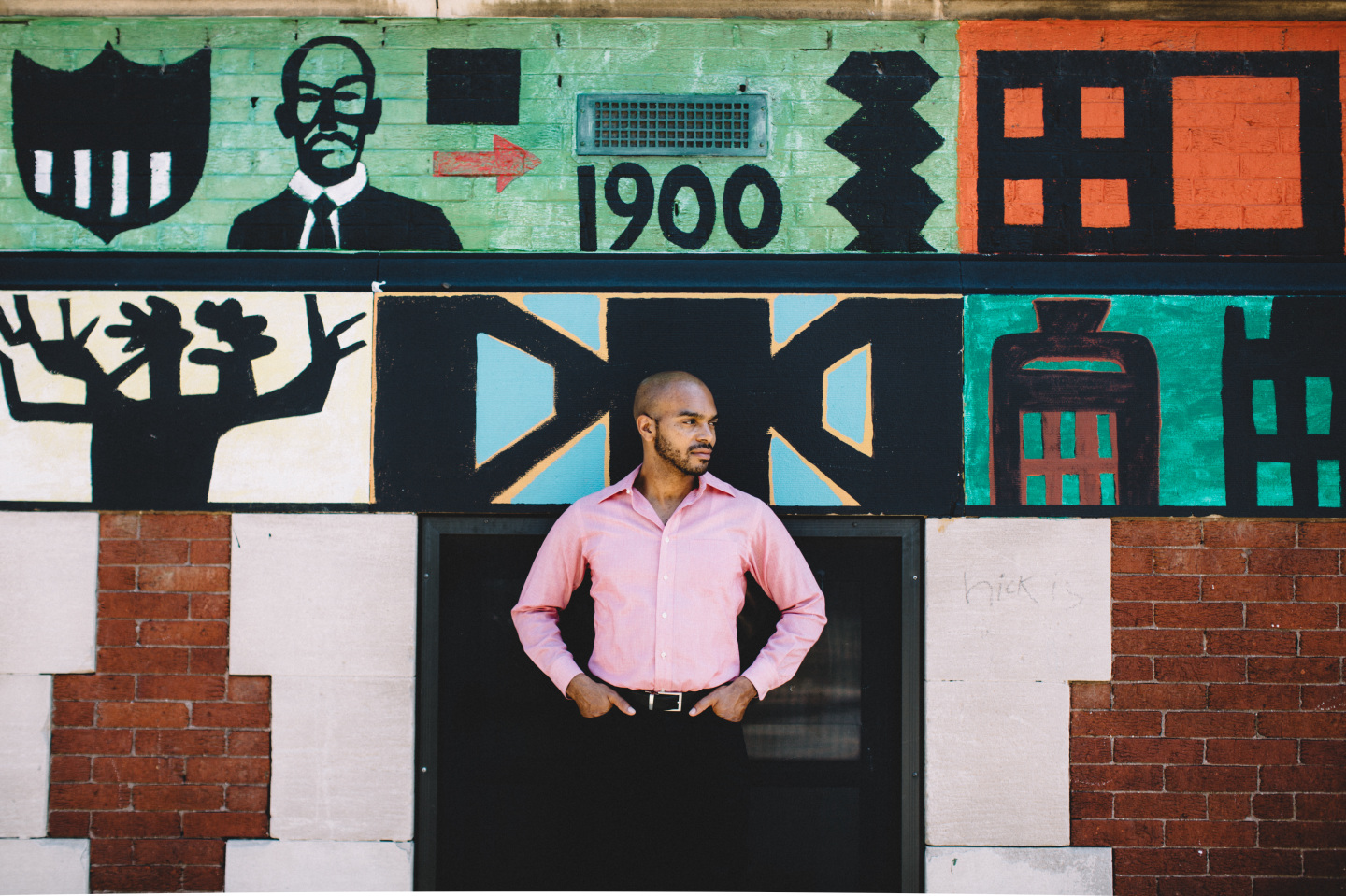 Man stands against a painted brick wall