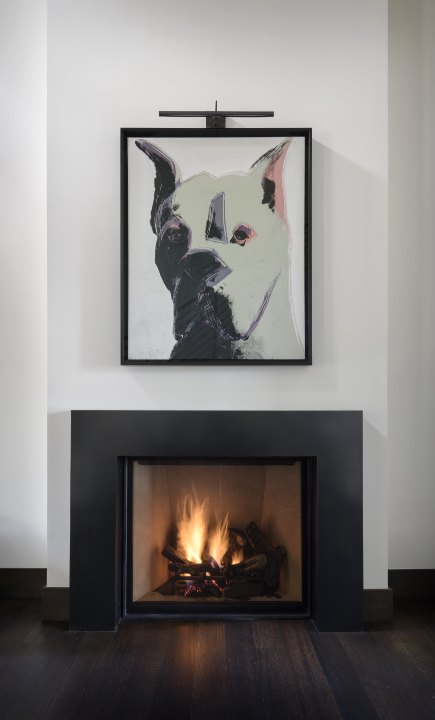 Andy Warhol painting of a dog hanging in front of fireplace.