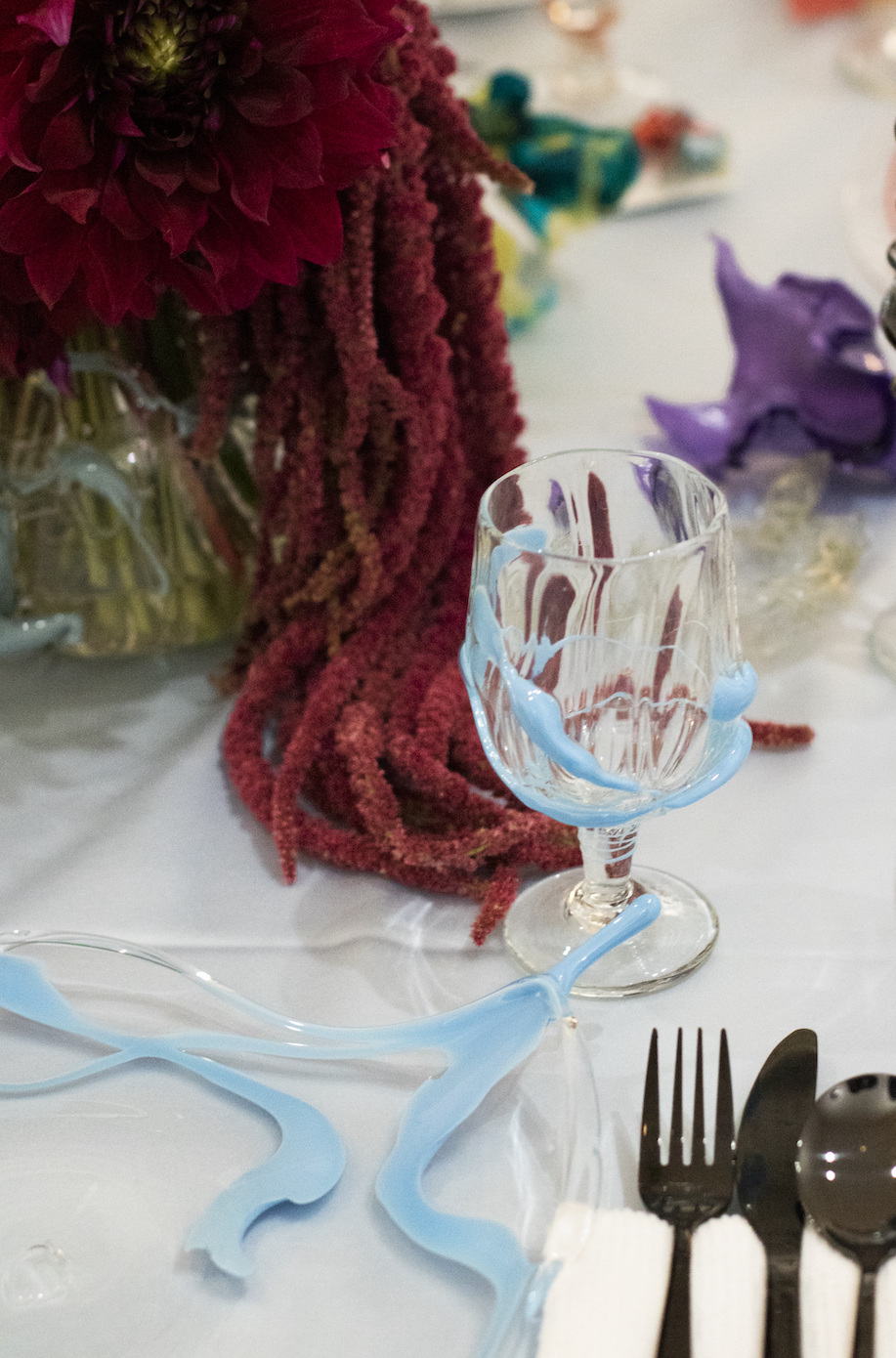 A wine glass and plate with light blue streaks on a dinner table.