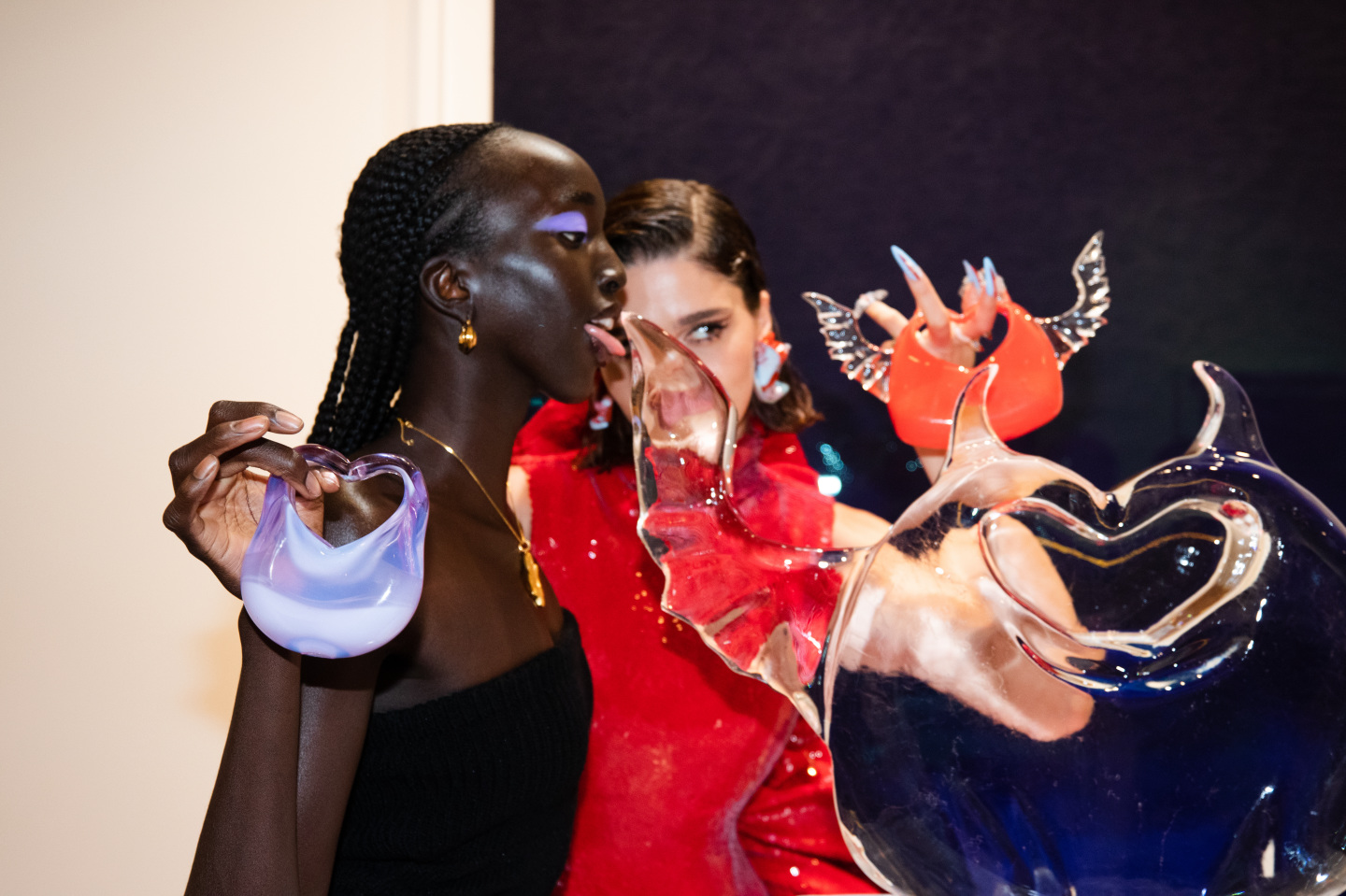 Two women posing with an ice sculpture and glass bags by HEVEN.