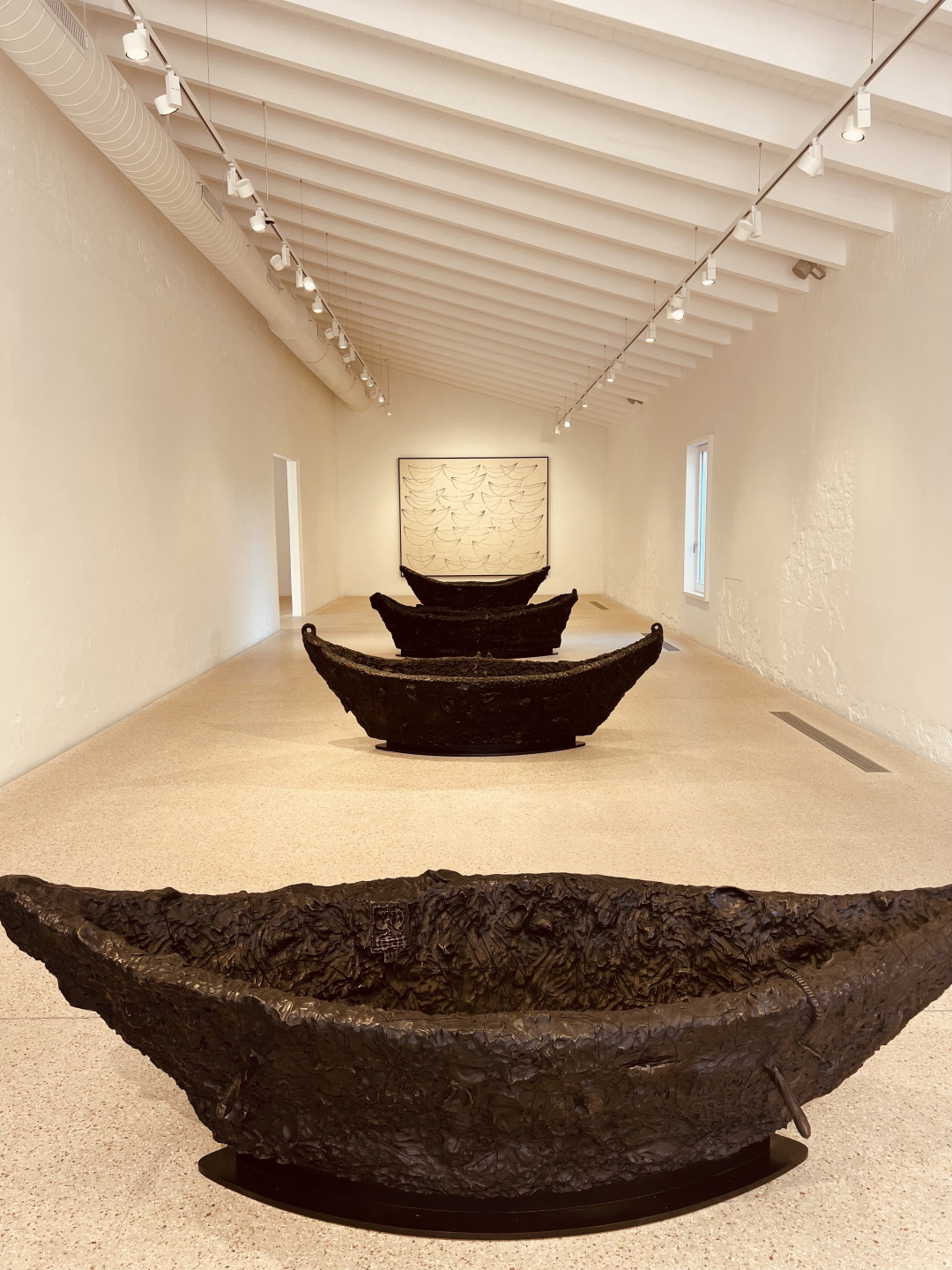 Four bronze boat sculptures in a parallel line.