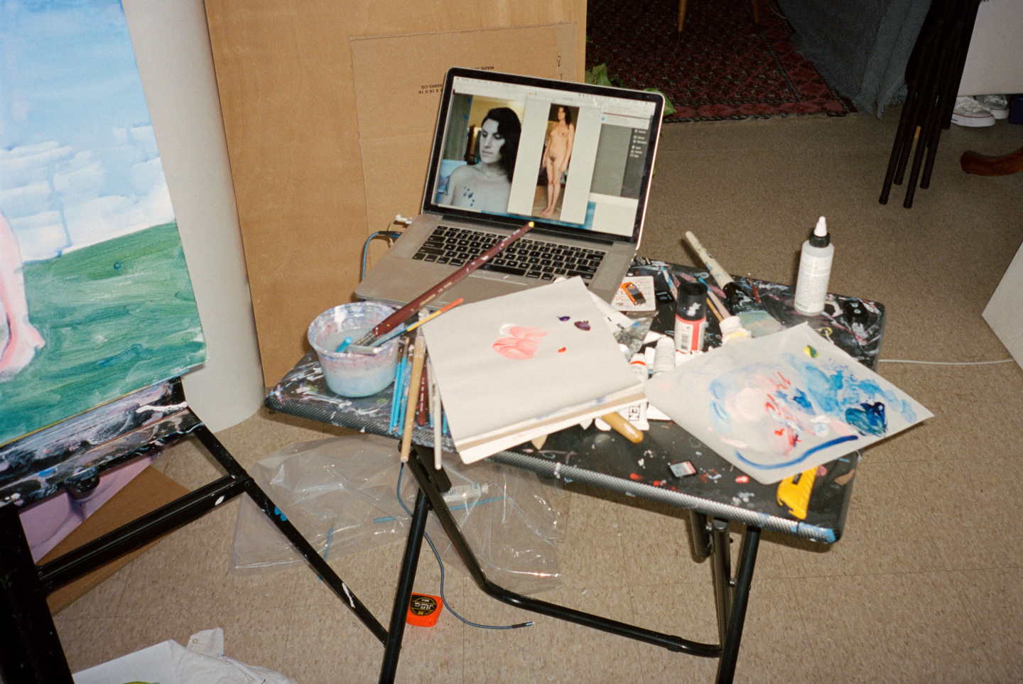 laptop on table next to painting