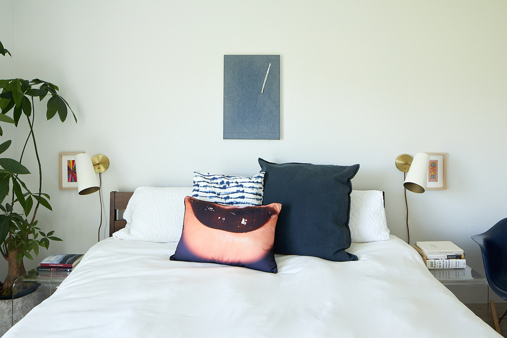 Primary bedroom with work above headboard by Sergej Jensen, talisman drawings by Sarah Cain, pillow by Marilyn Minter.