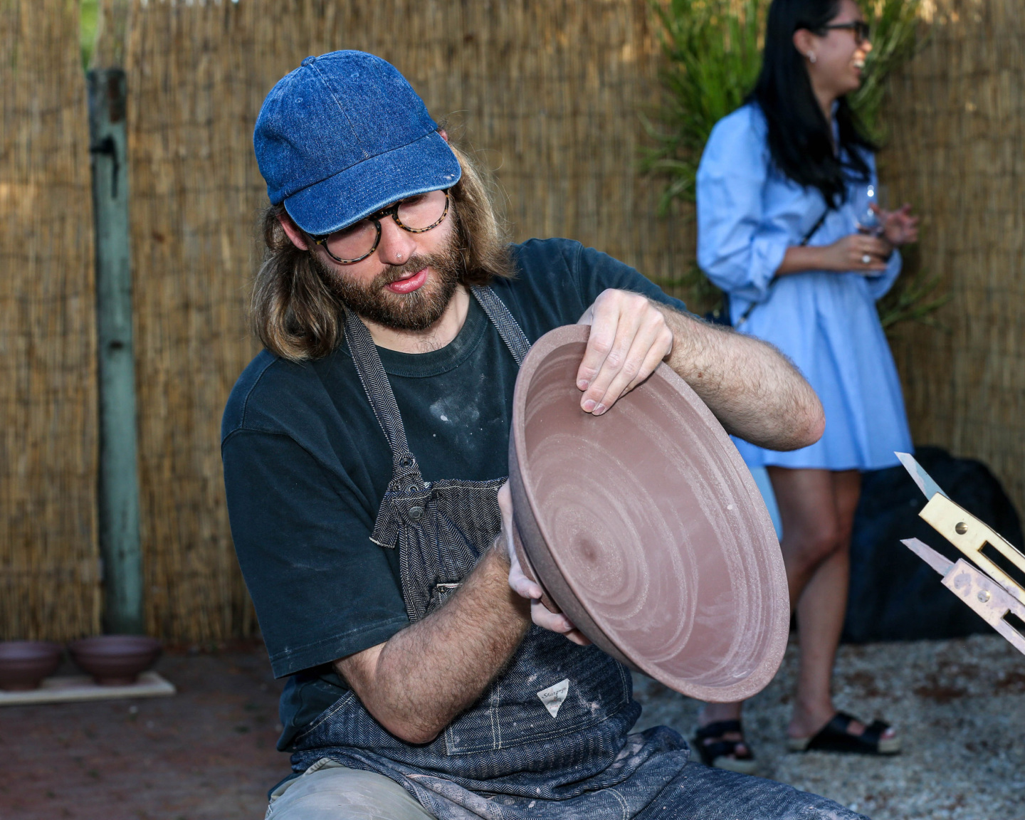 artist works on ceramic bowl in outdoor space