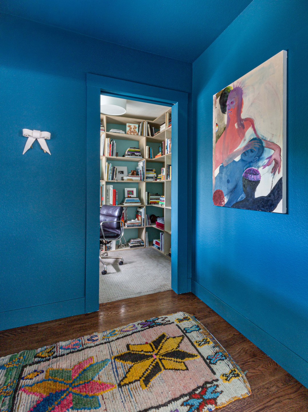 Artwork hanging in a blue room inside a home.