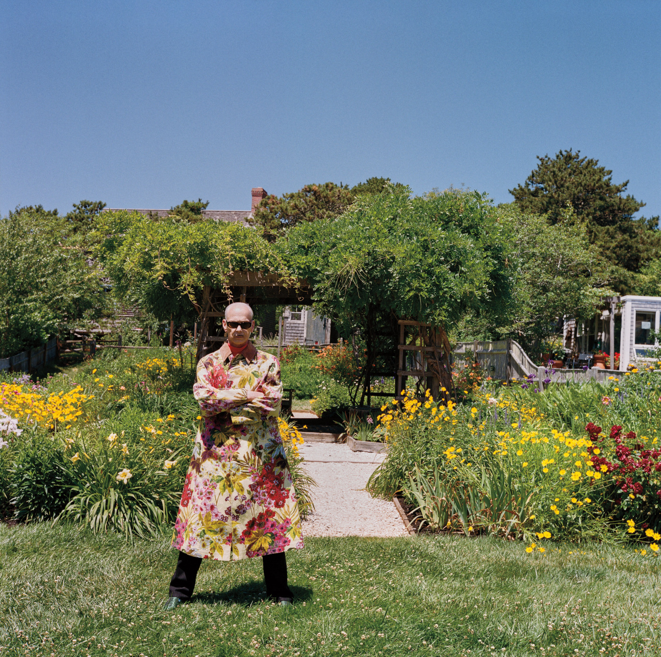 A man standing in front of a garden and trees.