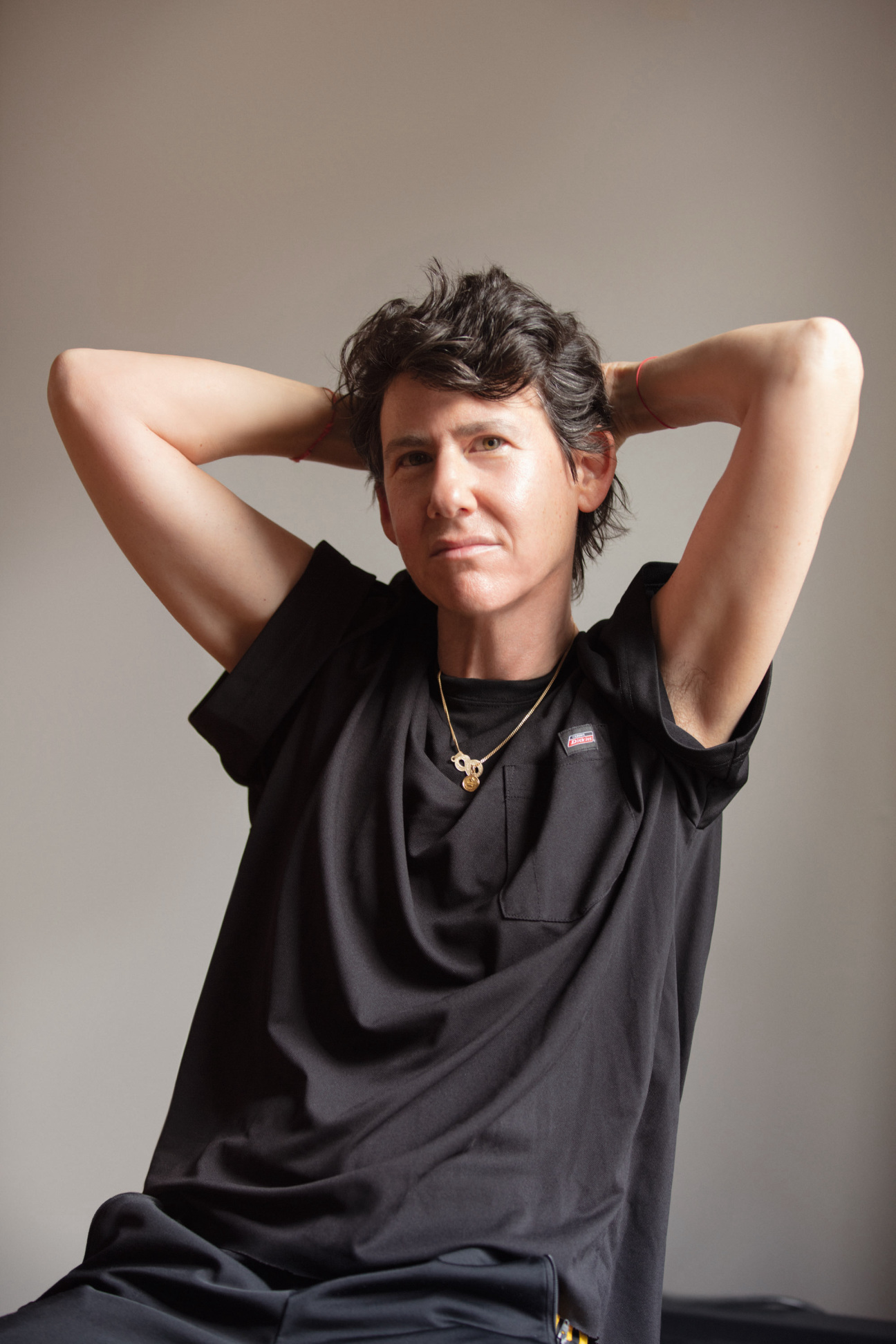 A woman sitting in a chair with her arms behind her head.
