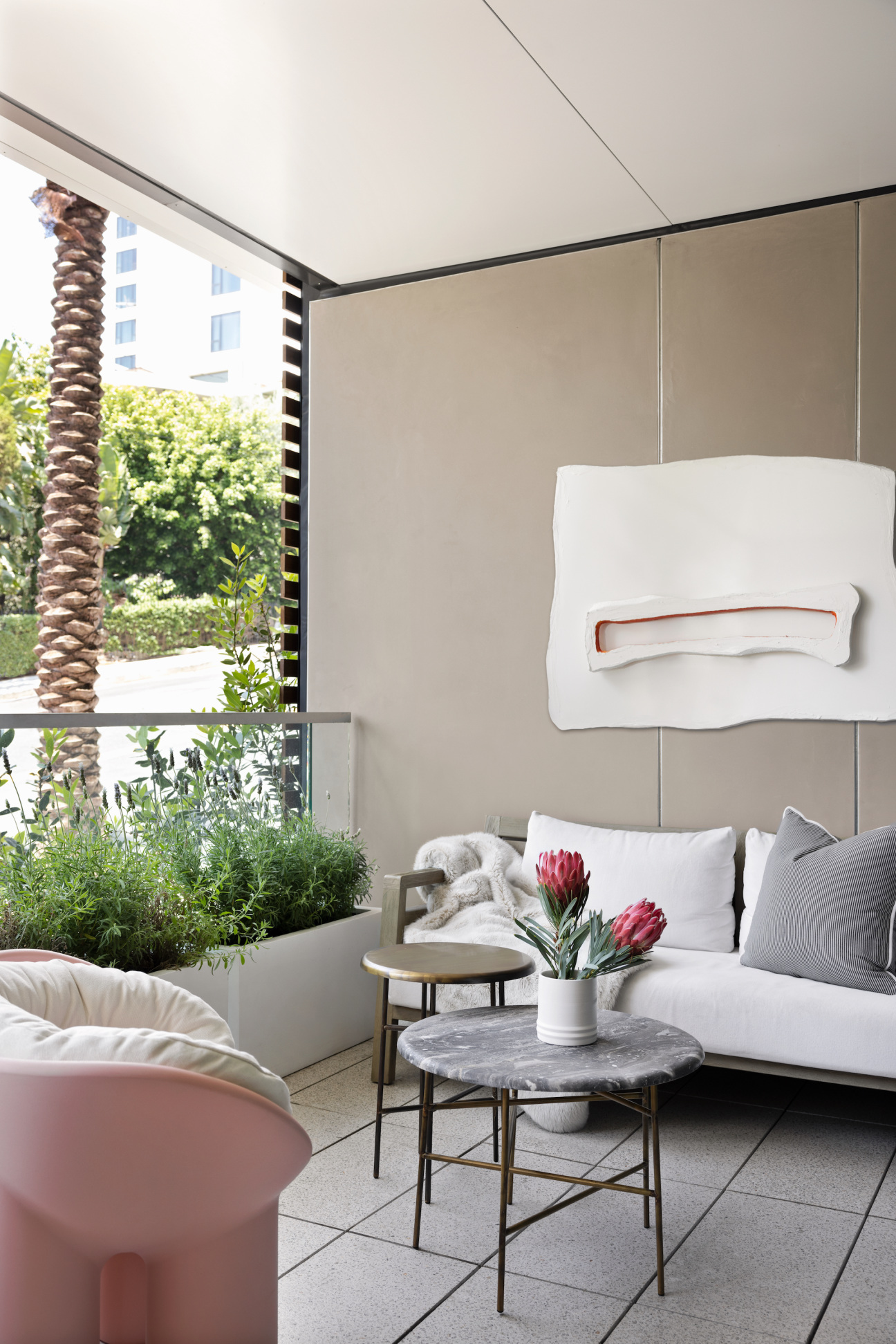 flat wall sculpture hangs above couch on terrace