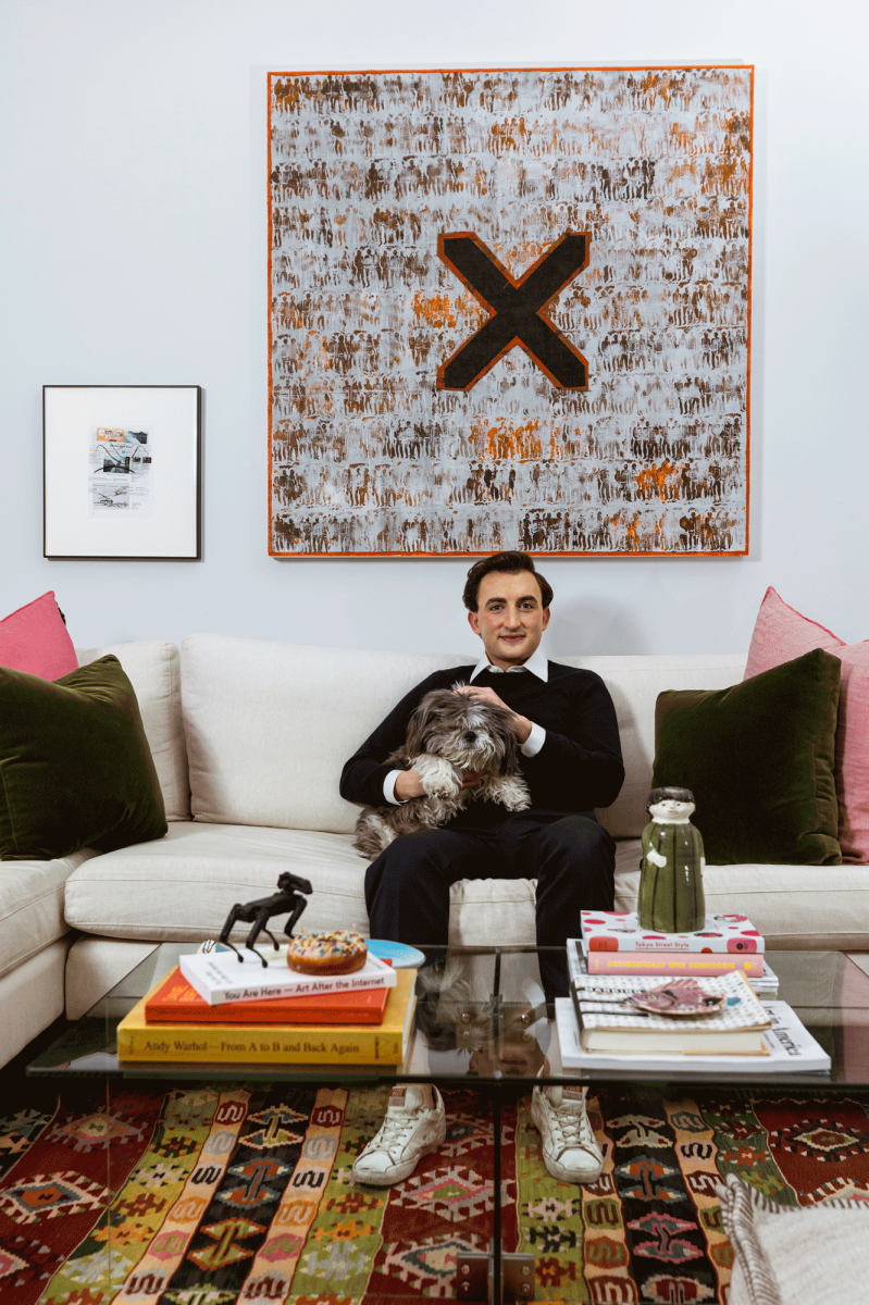 man on sofa with dog and art hanging behind