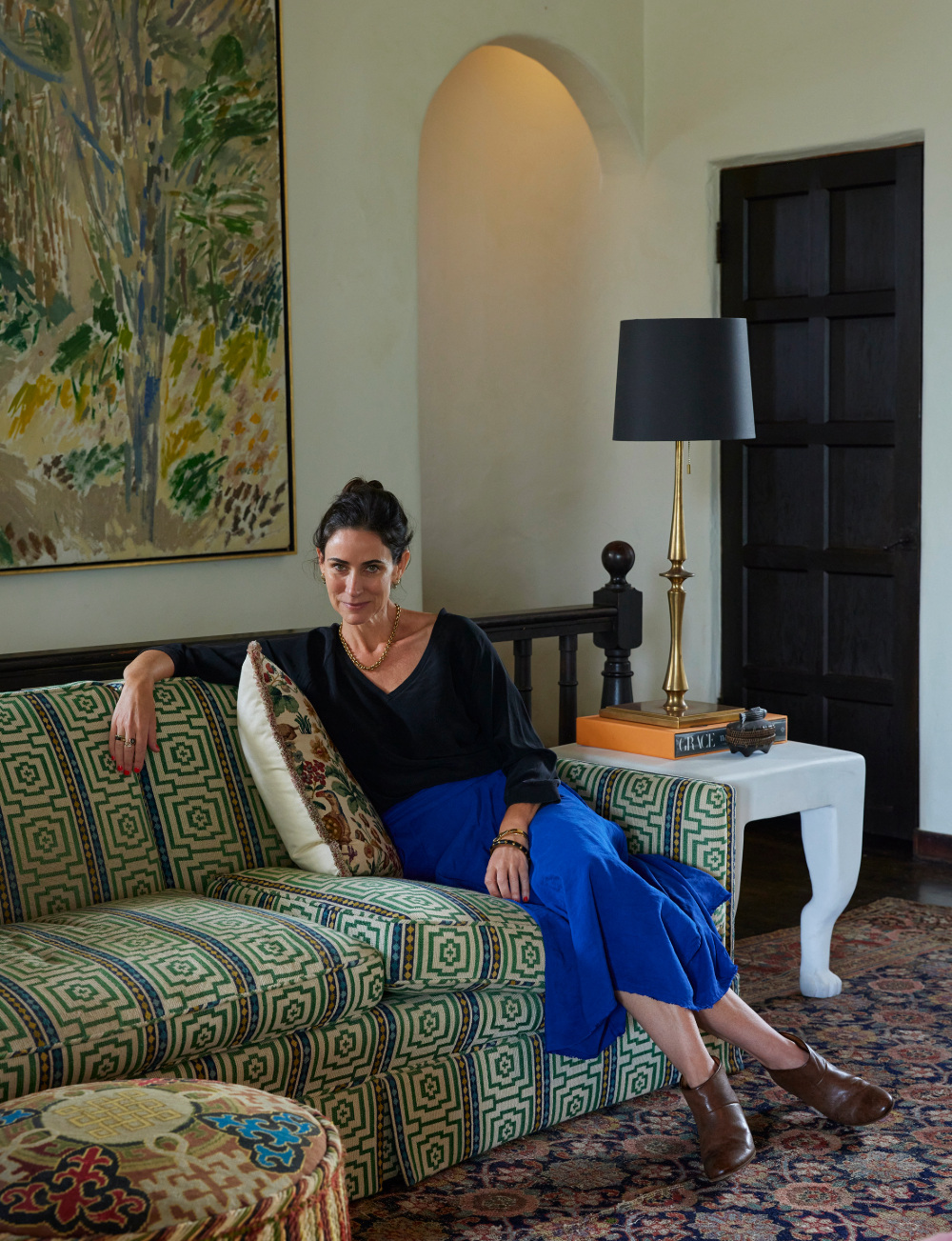 Woman sitting on a green couch, smiling at the camera.