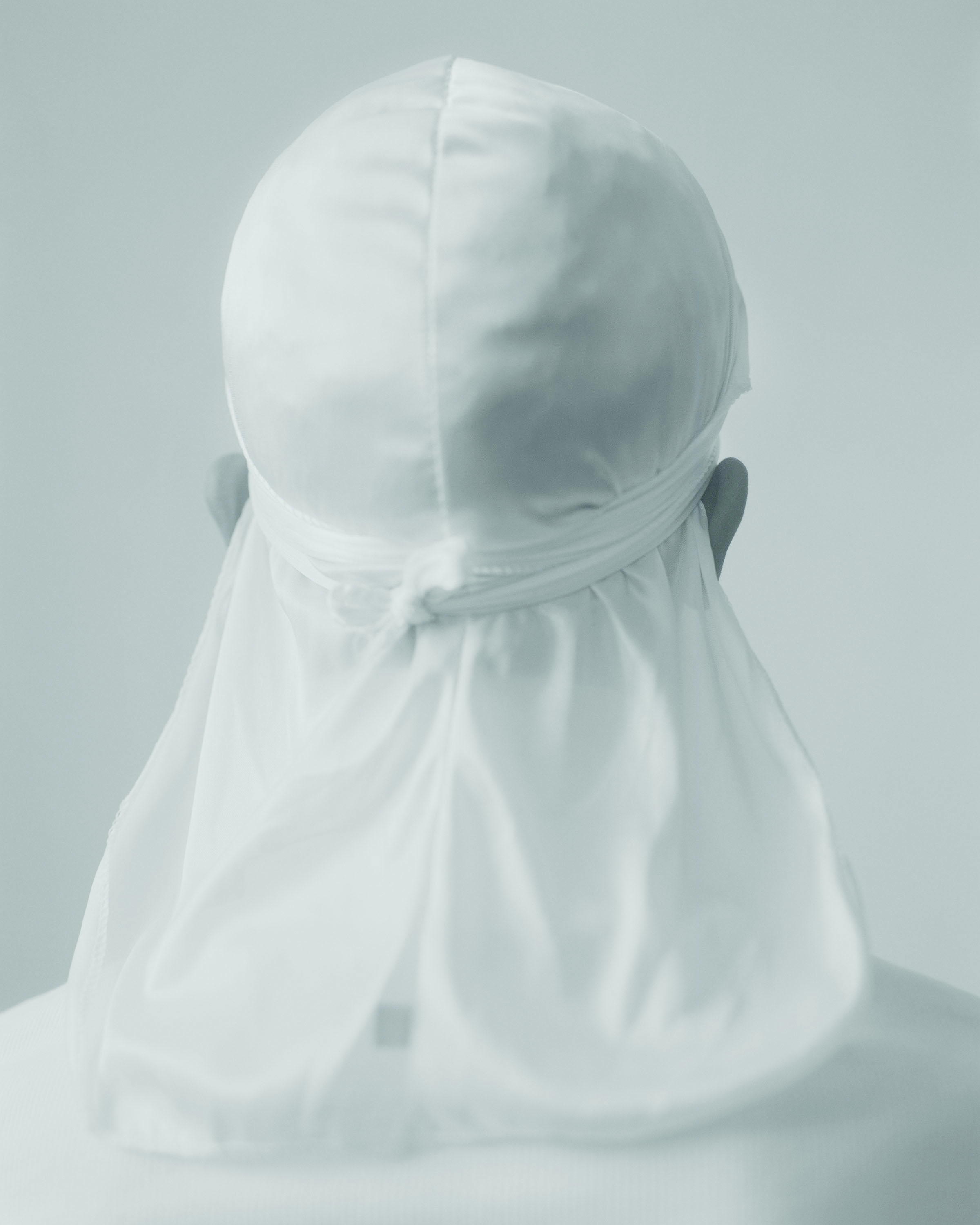 John Edmonds’ <i>Untitled (Du-Rag 1)</i>, 2017.” width=”2400″ height=”3000″><figcaption>John Edmonds’ <i>Untitled (Du-Rag 1)</i>, 2017.</figcaption></figure></p></p><p>The photographer John Edmonds first picked up a camera when he was 15 years old. His older sister had a Kodak point-and-shoot camera he would use to capture his life in Washington, D.C. At some point, the young lensman decided that he would picture black boys coming of age.</p><p>Almost 15 years later, those early images continue to inform his work: In a 2016 public commission, Edmonds mounted an image from his series <em>Hoods</em>—of hooded figures whose backs face the camera, obscuring their identity—on a 48-foot-tall billboard on West 29th Street in Manhattan. The billboard, presented by the arts organization 14×48, was a way of discussing racial profiling and how identity is imposed and fashioned. “Making photographs is like a way to learn how to see or understand how you see the world around you,” explains Edmonds, who received his M.F.A in photography from Yale University School of Art in 2016. “That was my main reason,” he says, for picking up a camera.</p><div class=