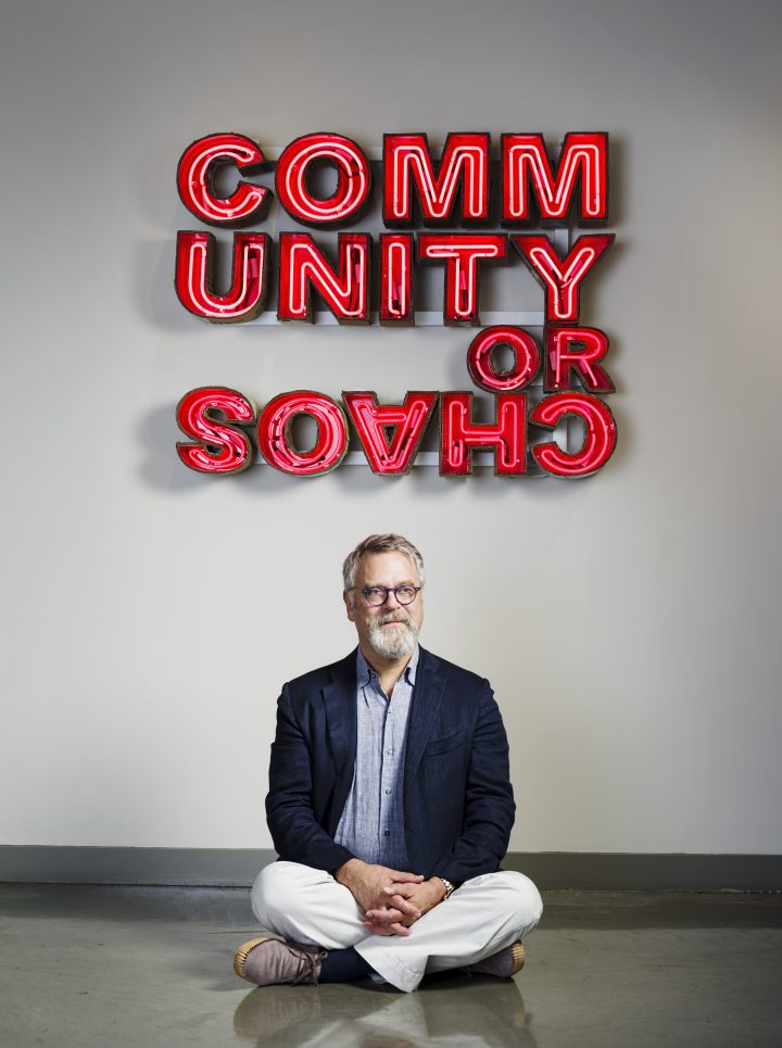 Andrea Bowers’s Community or Chaos, 2016, hangs above Nion McEvoy at his Chronicle Books office.