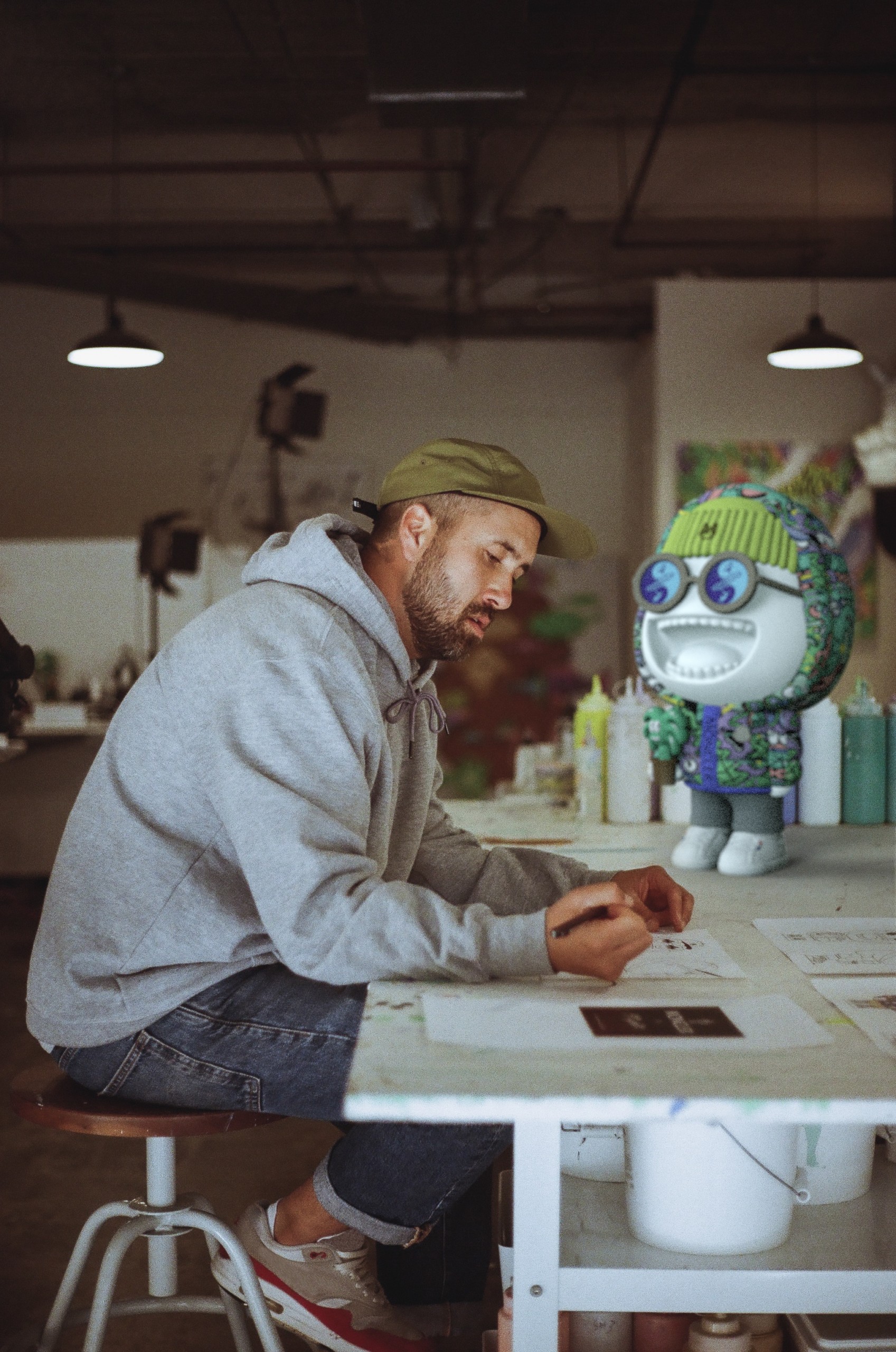 steven harrington sitting at work table with moncler pupazzo statue next to him