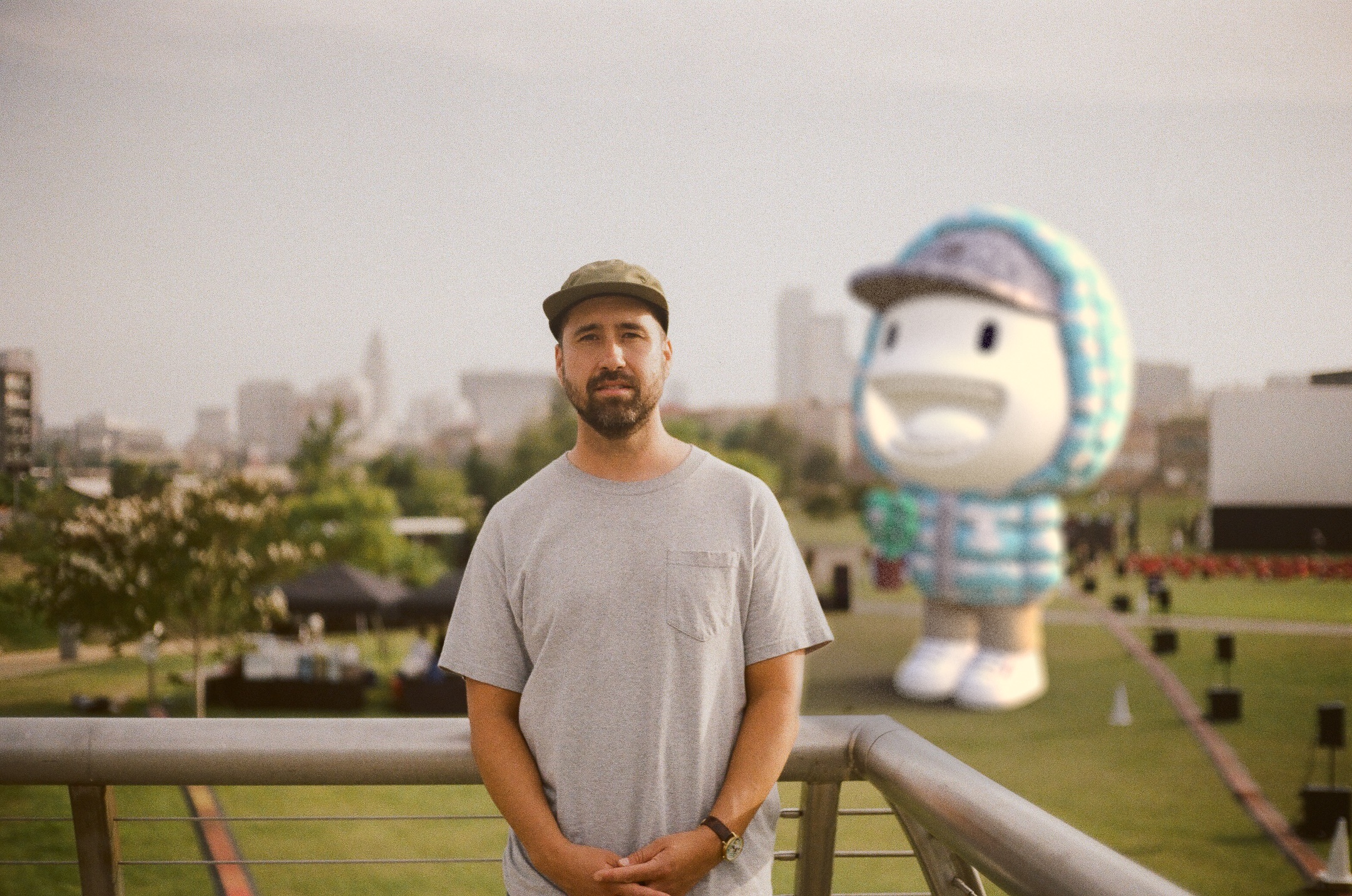 Steven Harrington standing on a balcony with large moncler pupazzo statue behind him