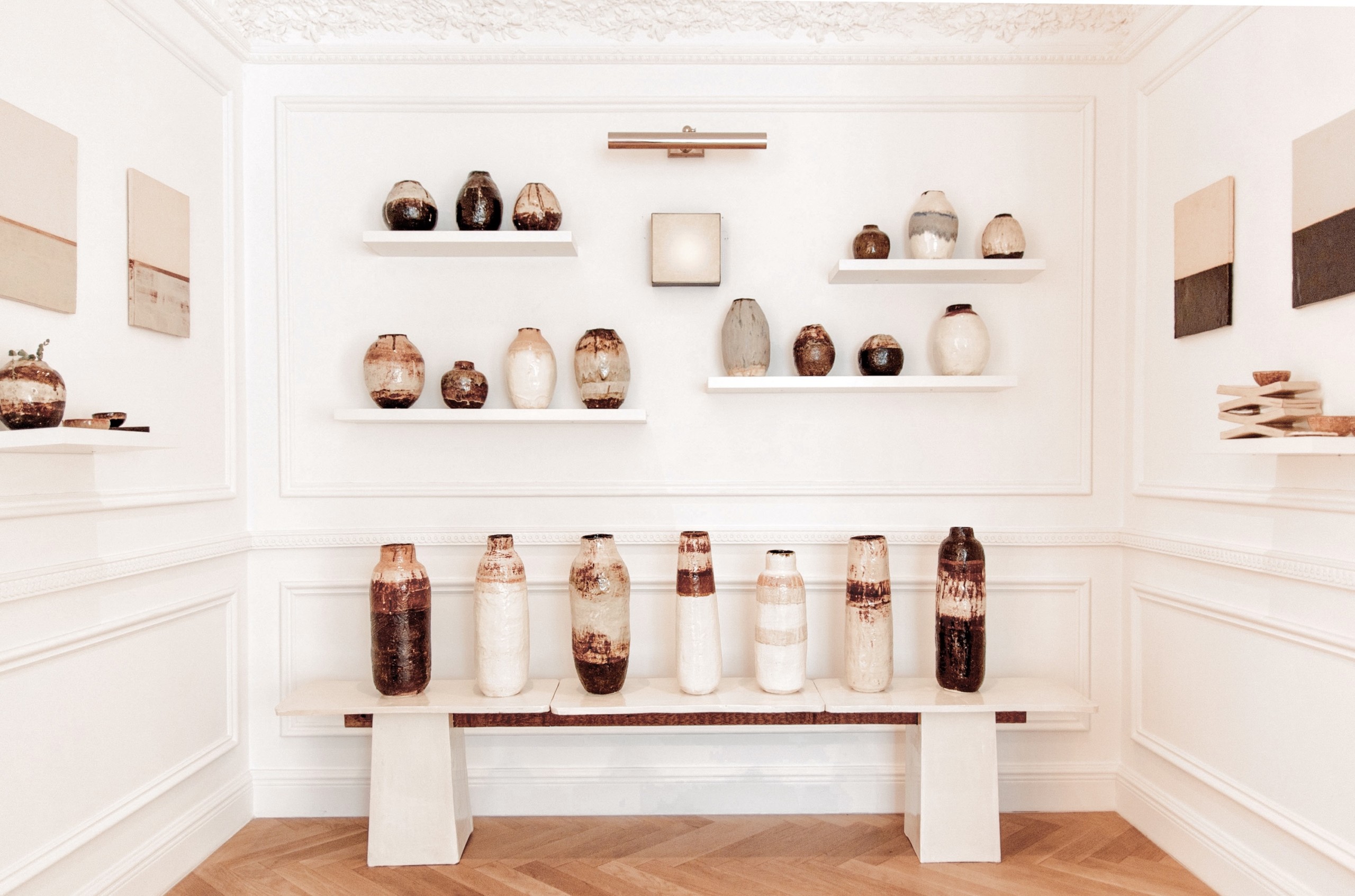 installation of earthy pottery, on benches and shelves in alcove