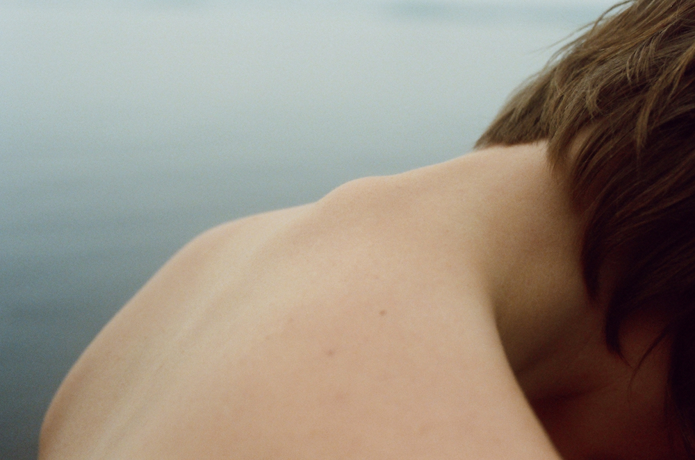 “a photo of the back of the neck and spine of a woman with water in the background from Lina Scheynius photo-essay for Tabayer jewelry Tabayer jewellery