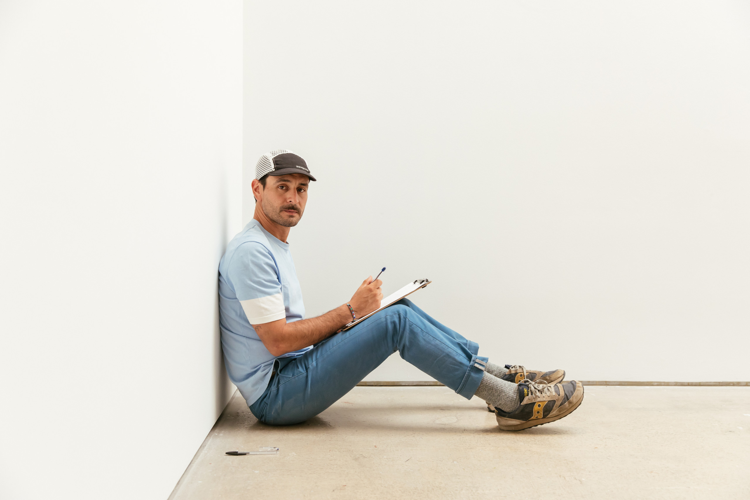 Gabriel Rico sits on the floor with clipboard and pen in hand.